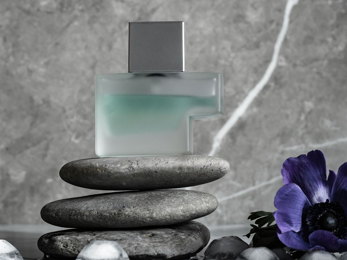 Unbranded perfume bottle on stacked stones (illustrative)