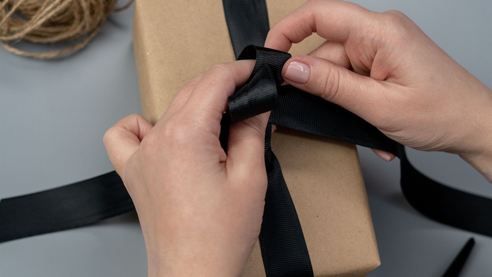 Hands wrapping an online order with a black ribbon