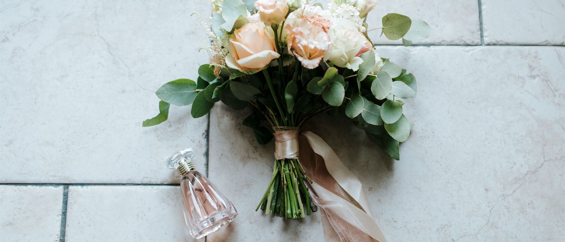 Flowers, perfume and rings arranged on stone tiles