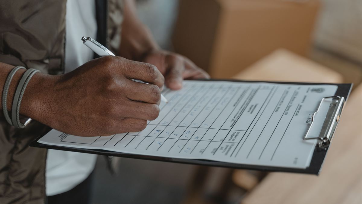 Hand ticking items on a clipboard checklist